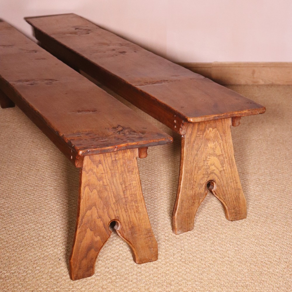 A handcrafted oak trestle dining table featuring an adzed tabletop, keyed stretcher joint, and two matching solid oak benches. View X
