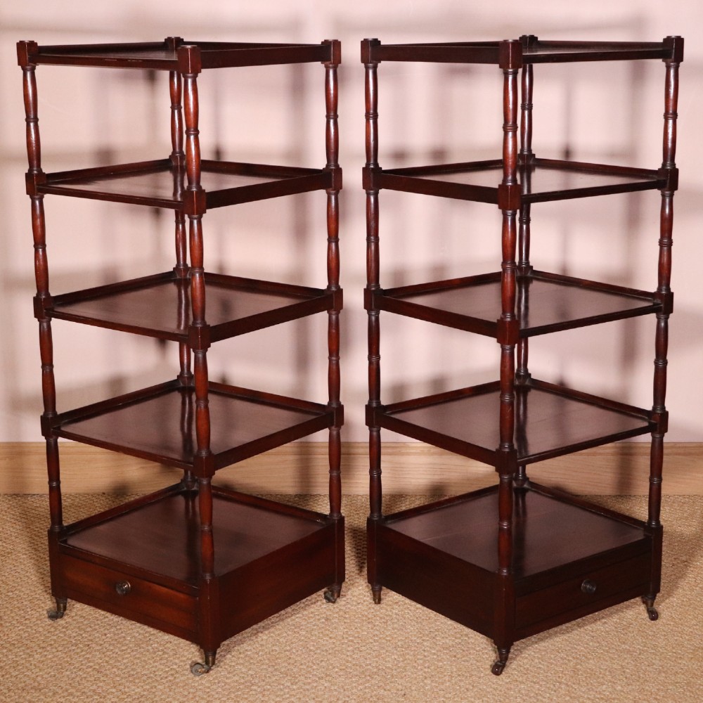 A matching pair of George IV mahogany whatnots featuring five open tiered shelves with turned supports, a single base drawer, and brass castors.