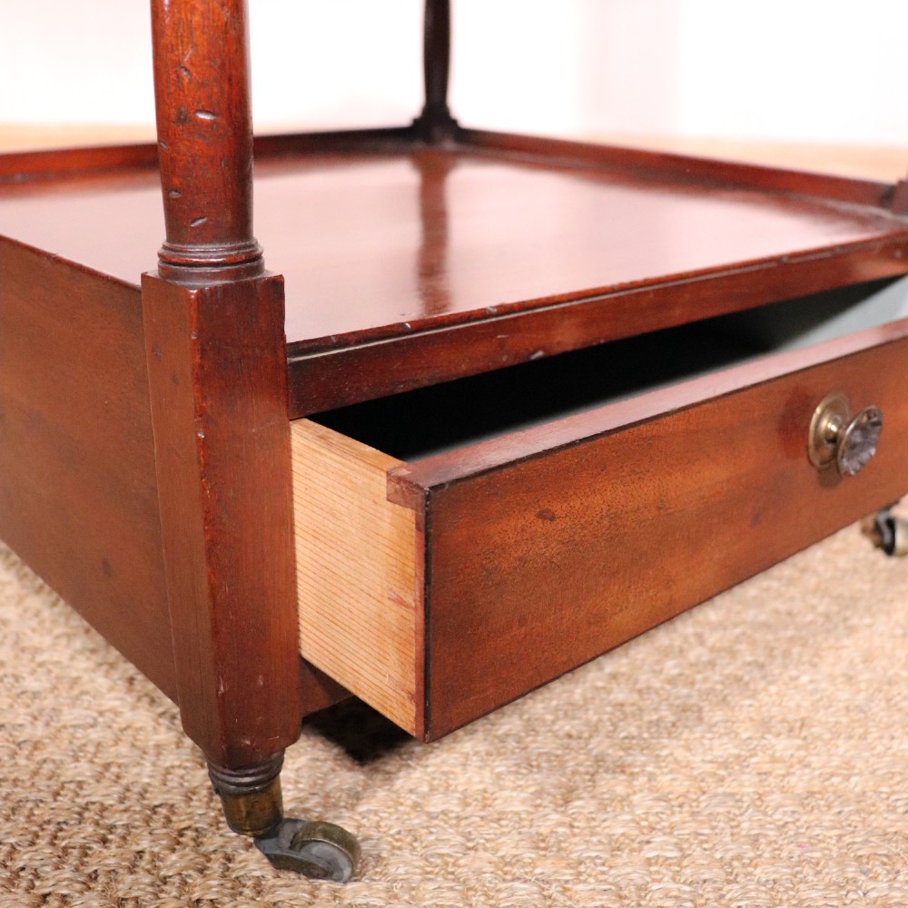 A matching pair of George IV mahogany whatnots featuring five open tiered shelves with turned supports, a single base drawer, and brass castors. View V