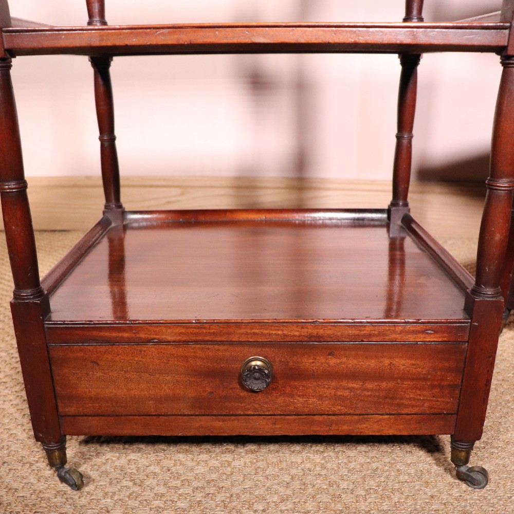 A matching pair of George IV mahogany whatnots featuring five open tiered shelves with turned supports, a single base drawer, and brass castors. View VI