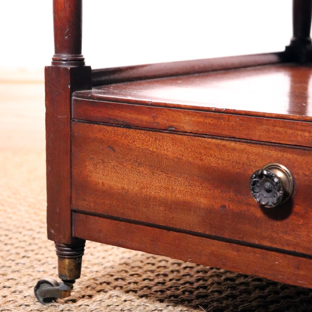 A matching pair of George IV mahogany whatnots featuring five open tiered shelves with turned supports, a single base drawer, and brass castors. View X