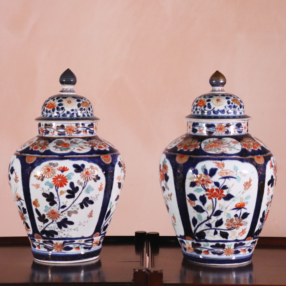 A pair of early eighteenth-century Japanese Arita porcelain lidded jars decorated with cobalt blue, red, and gold floral patterns.