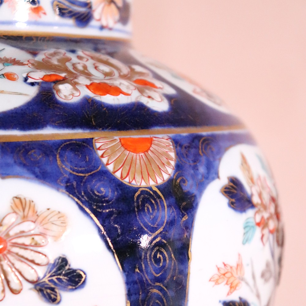 A pair of early eighteenth-century Japanese Arita porcelain lidded jars decorated with cobalt blue, red, and gold floral patterns. View V