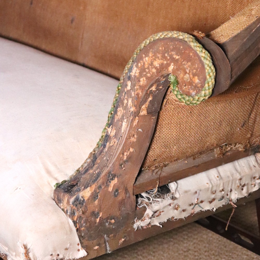 An antique Chippendale style mahogany settee featuring a serpentine camel back, scrolled arms, pierced stretchers, and exposed base lining fabric. View VI