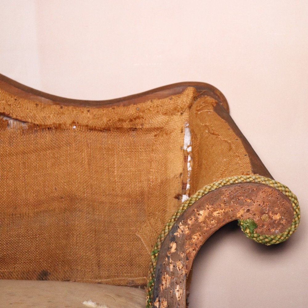 An antique Chippendale style mahogany settee featuring a serpentine camel back, scrolled arms, pierced stretchers, and exposed base lining fabric. View XI