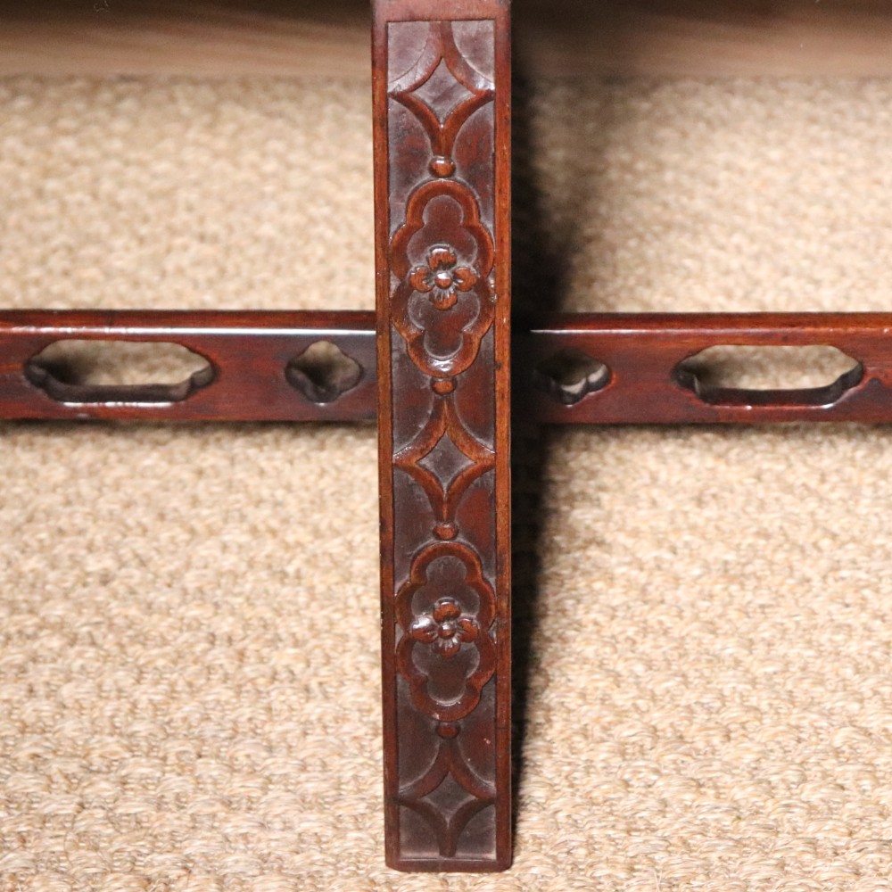 An antique Chippendale style mahogany settee featuring a serpentine camel back, scrolled arms, pierced stretchers, and exposed base lining fabric. View XII