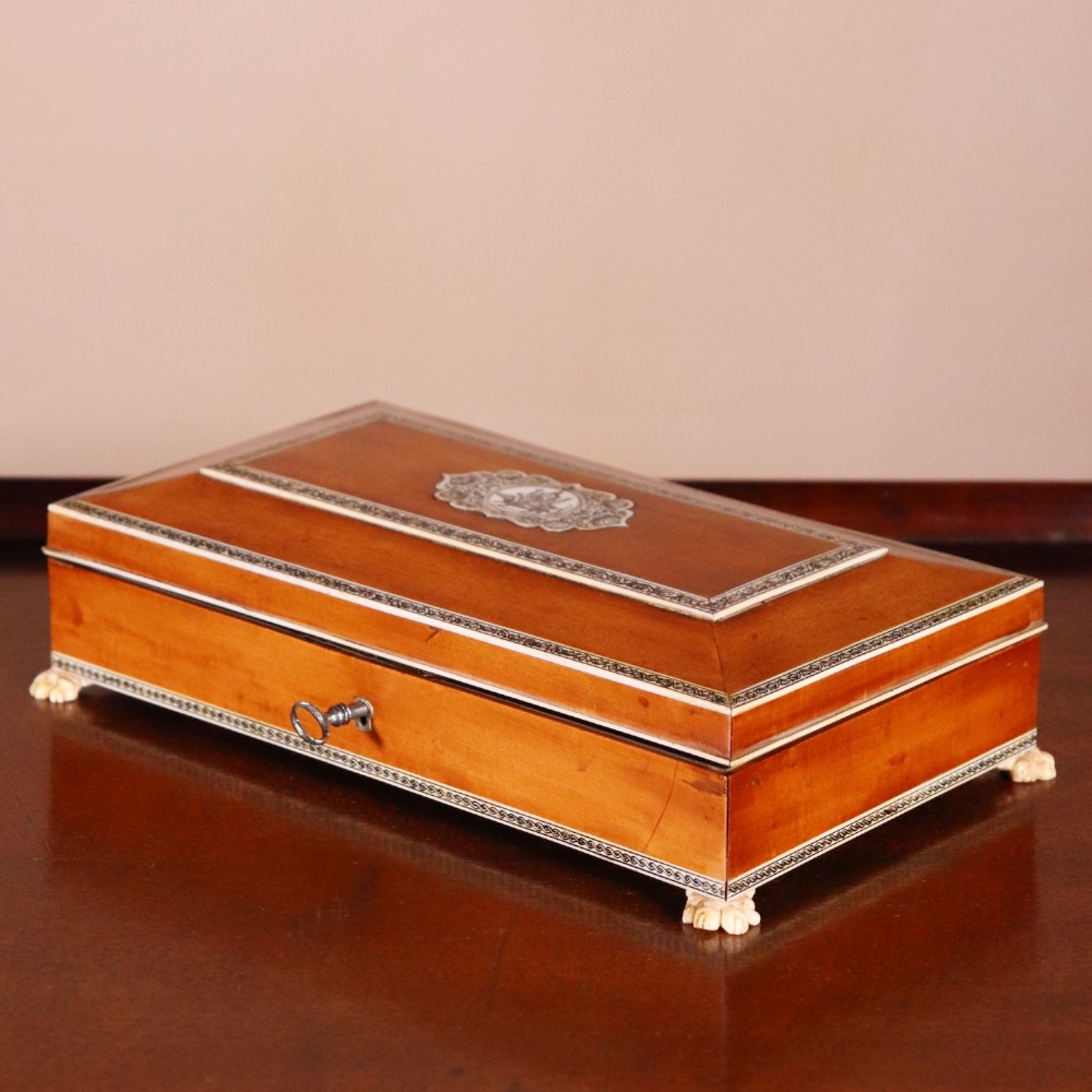 A rectangular sandalwood card box with penwork-engraved ivory borders, carved lion-paw feet, and a central medallion motif.