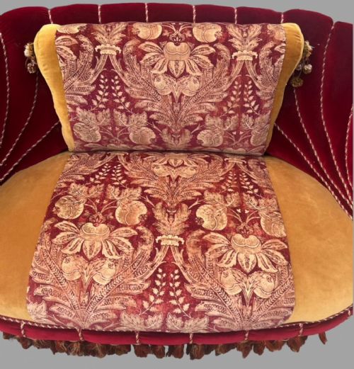 fig 1. An Austro-Hungarian shell-shaped sofa featuring deep red velvet scalloped back upholstery, a gold velvet seat with patterned brocade central panels, and dramatic tasselled fringe along the base.