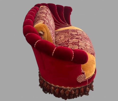 fig 2. An Austro-Hungarian shell-shaped sofa featuring deep red velvet scalloped back upholstery, a gold velvet seat with patterned brocade central panels, and dramatic tasselled fringe along the base.