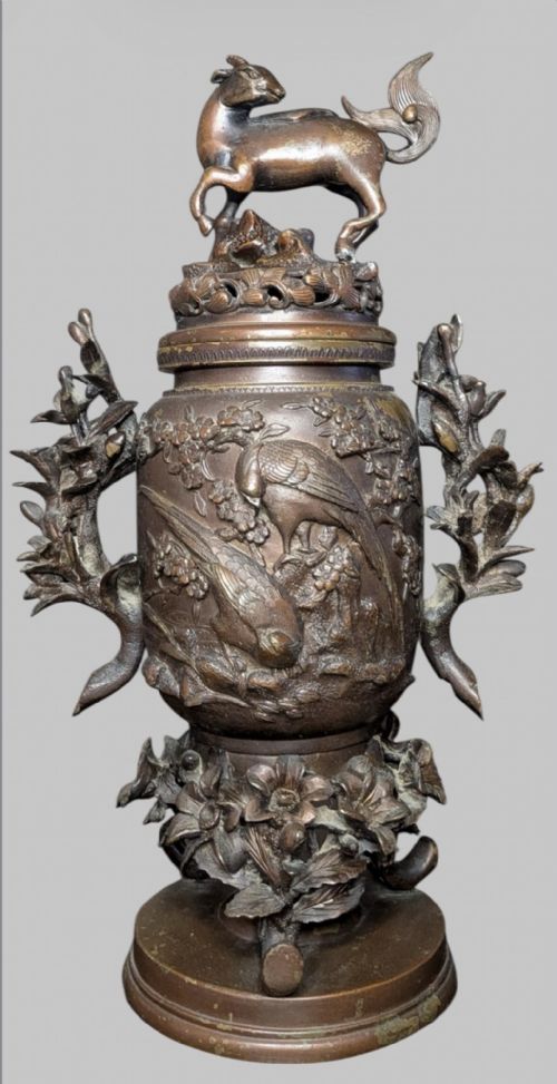 fig 1. An antique cast bronze Japanese incense burner featuring a goat finial, foliage handles, bird relief panels, and a stepped circular base.