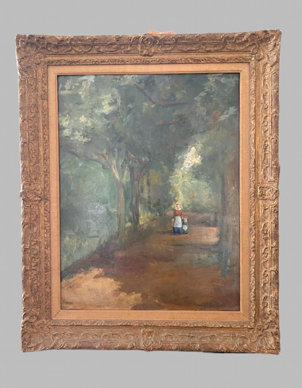An oil painting on board depicting a mother and child walking along a shaded woodland path, set within a heavily carved gilded frame.