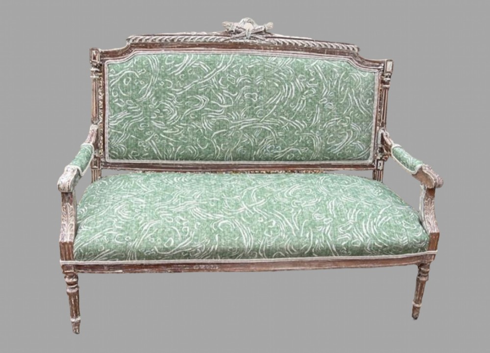 A French Louis XVI style canape featuring a distressed painted wood frame with fluted legs and patterned green upholstery.