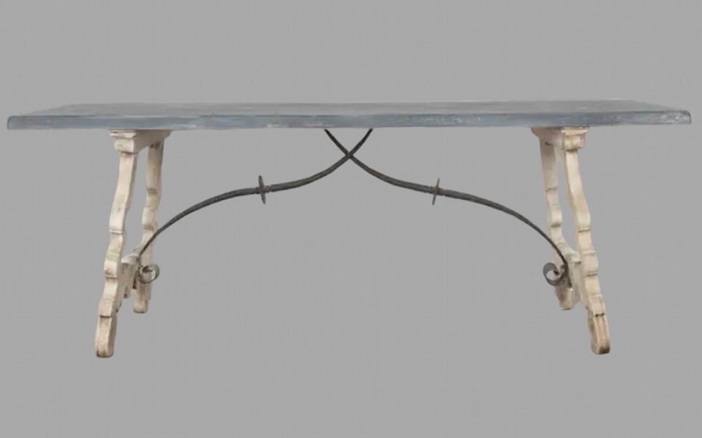 A rectangular dining table featuring a dark grey top resting on white painted trestle legs joined by a curved wrought iron stretcher.