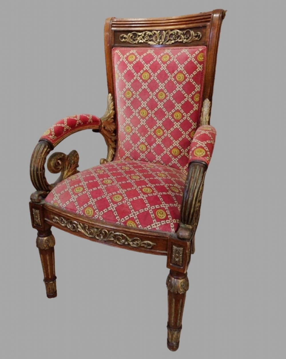 A Victorian Gothic Revival armchair made from carved gilded beechwood with red patterned fabric upholstery.
