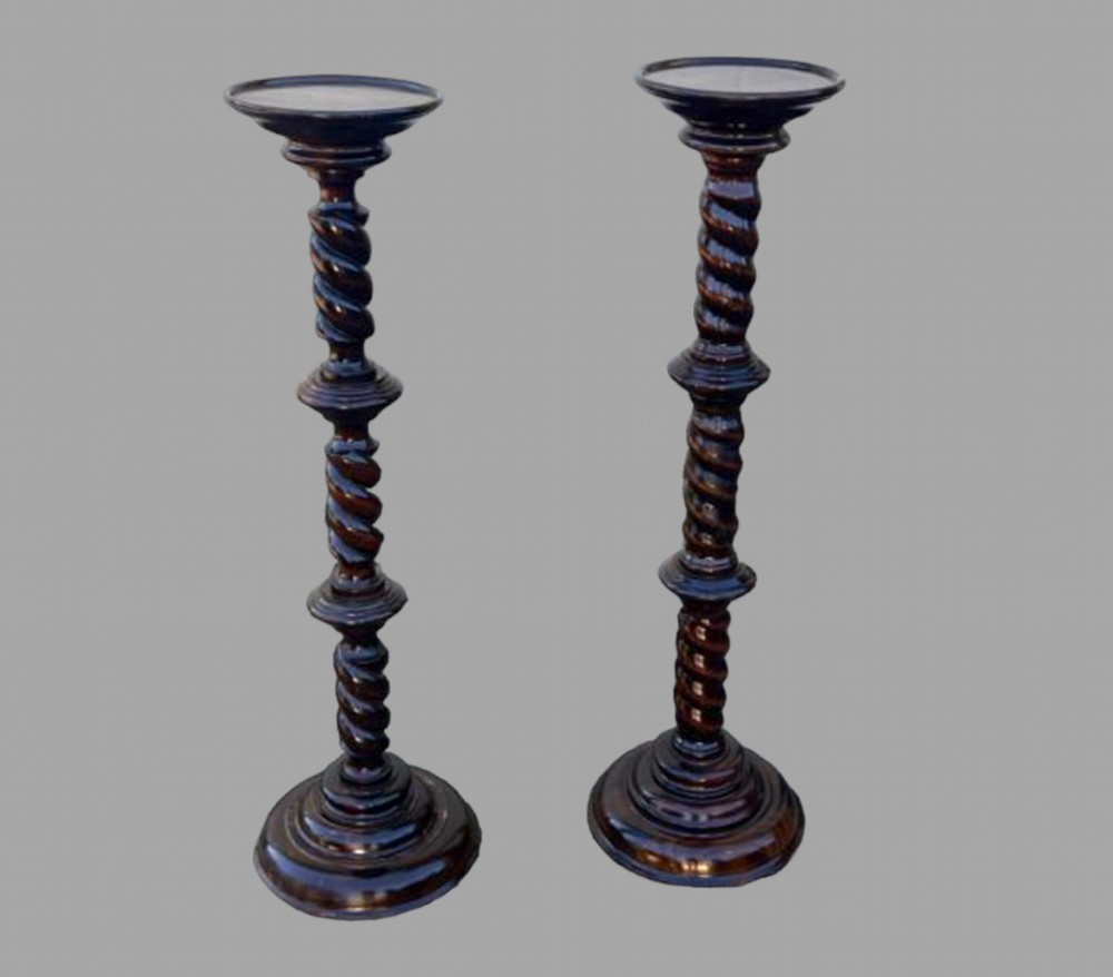 A pair of dark hardwood torchiere plant stands featuring barley twist columns and circular stepped bases.