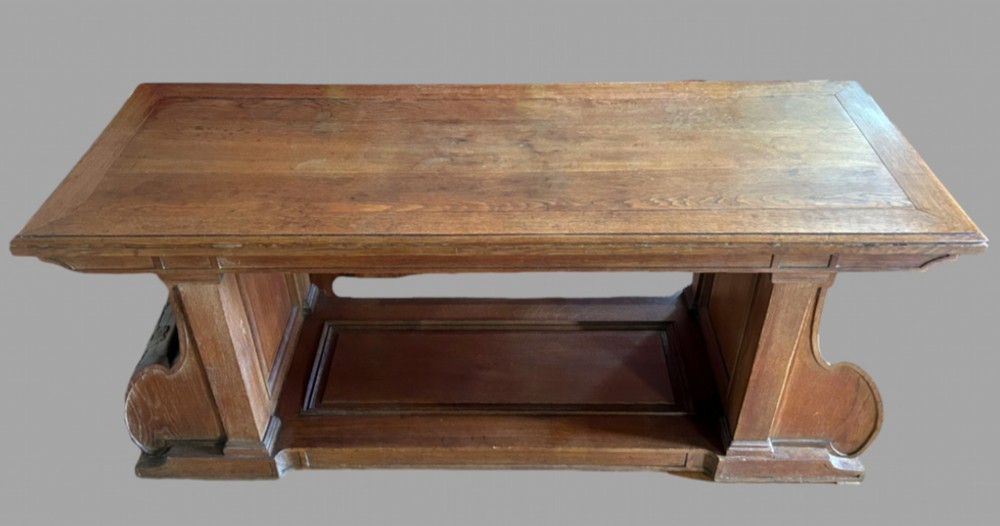 An overhead view of a rectangular antique oak hall table featuring a planked top, a lower stretcher shelf, and shaped pedestal supports.