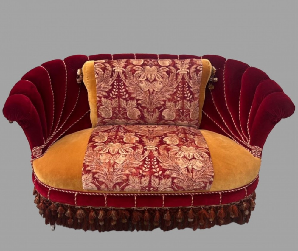 An Austro-Hungarian shell-shaped sofa featuring deep red velvet scalloped back upholstery, a gold velvet seat with patterned brocade central panels, and dramatic tasselled fringe along the base.