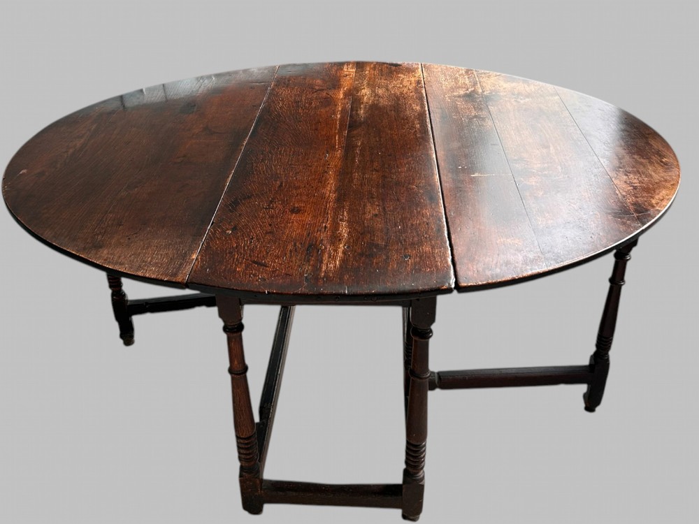 A 19th-century dark oak gateleg table with an extended oval drop-leaf top and turned legs.