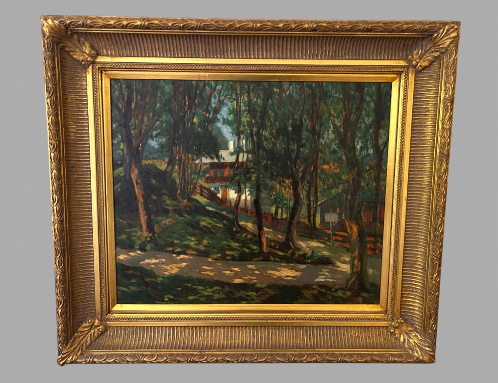 An impressionist oil painting depicting a house nestled behind tall woodland trees, housed within a wide, fluted gilt wooden frame.