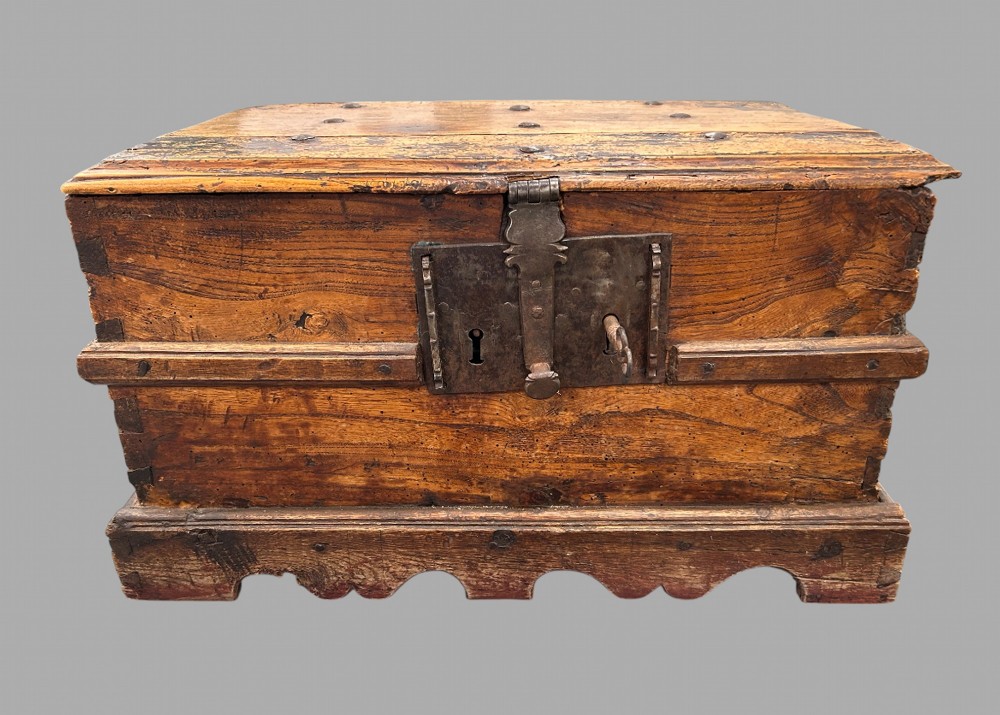 An eighteenth-century Spanish walnut storage box with a large wrought-iron lockplate, key, and a scalloped plinth base.