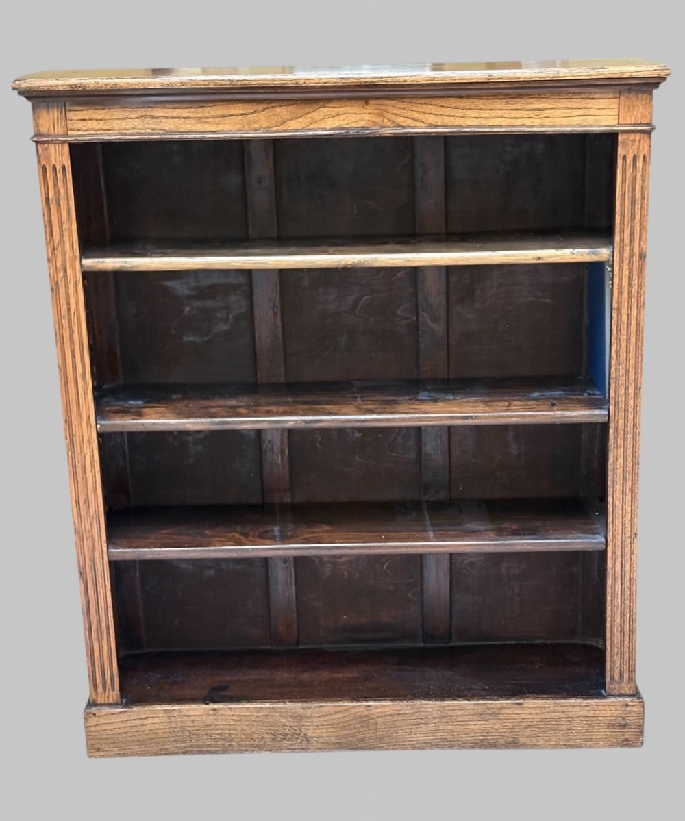 An upright rectangular wooden bookcase featuring four open tiers, fluted pilasters on the sides, and a projecting top cornice.