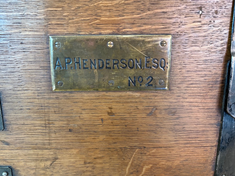 A Victorian oak travelling trunk fitted with heavy iron corner mounts, central iron lock strap, and an engraved brass nameplate. View IX