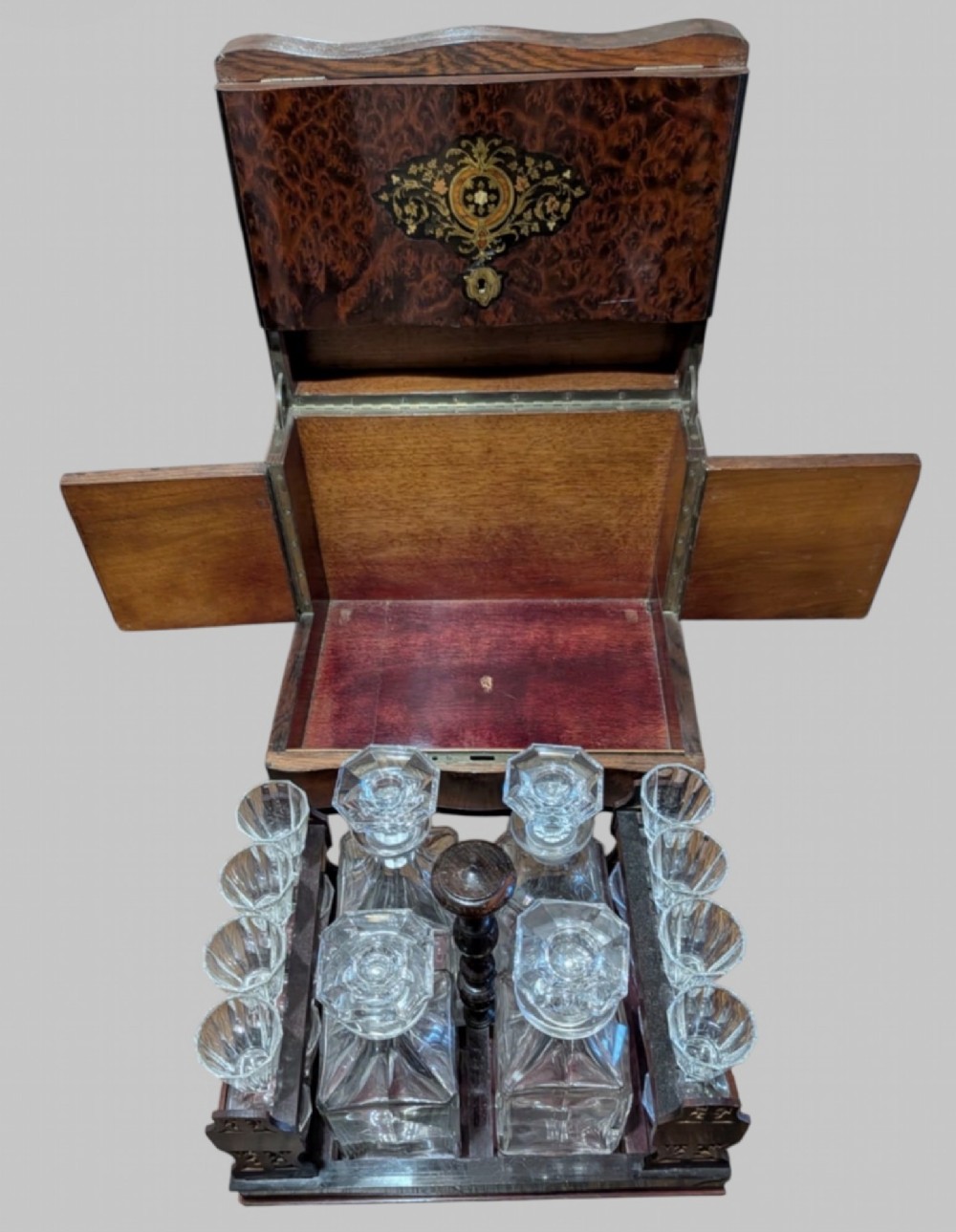 An open 19th-century French Napoleon III wooden cave a liqueur box featuring inlaid lid detailing and a removable tier holding cut-glass decanters and small glasses.