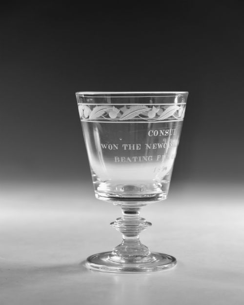 fig 2. An antique clear glass Georgian rummer featuring wheel-engraved inscriptions and foliage motifs above a knopped stem.