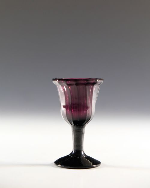 fig 1. A Georgian amethyst purple glass egg cup with a fluted bowl, slender stem, and circular pedestal foot.