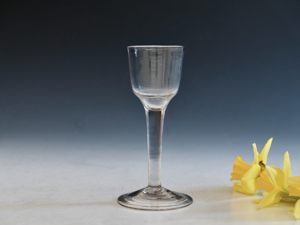 An eighteenth century plain stem wine glass made from clear lead glass featuring a bucket bowl and a folded foot.
