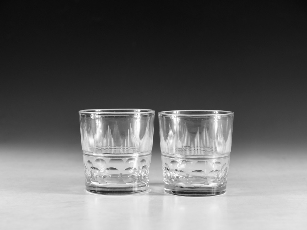 A pair of clear antique glass tumblers featuring hand-cut decorative bands and engraved geometric motifs.
