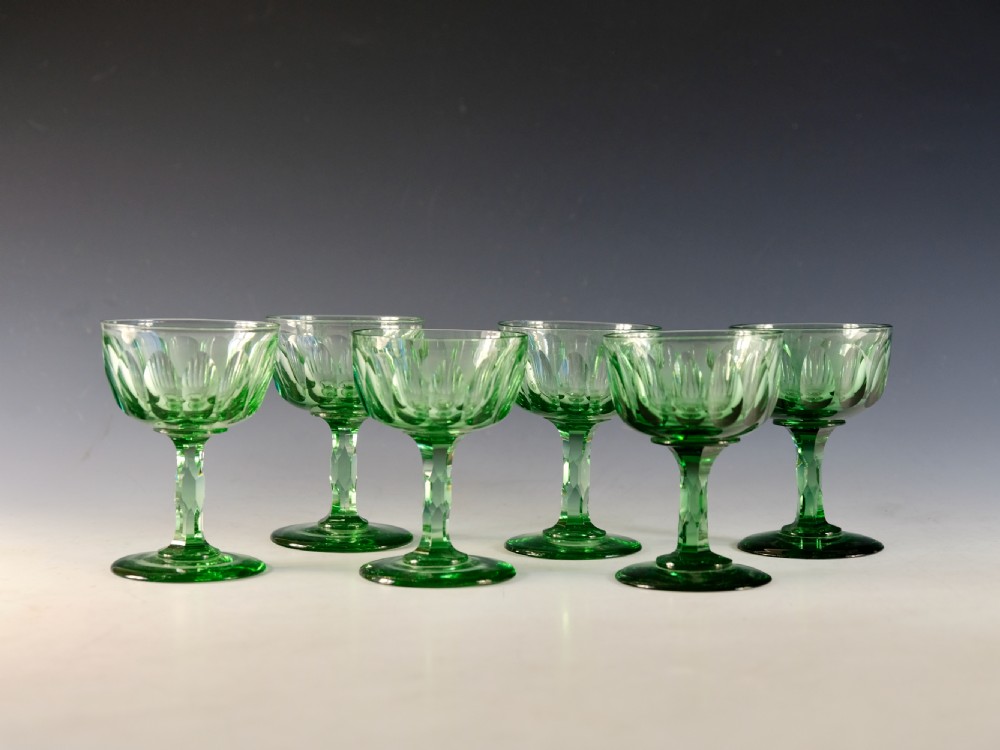 A set of six light green antique champagne glasses featuring faceted stems and scalloped bowls.