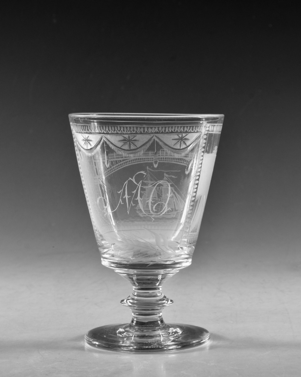 An antique clear lead glass rummer featuring detailed wheel engraving of a sailing ship beneath a bridge, set on a knopped stem and circular foot. View IV