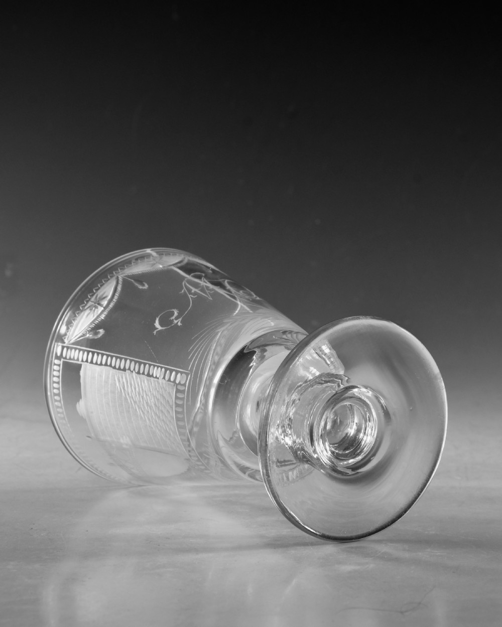 An antique clear lead glass rummer featuring detailed wheel engraving of a sailing ship beneath a bridge, set on a knopped stem and circular foot. View VI