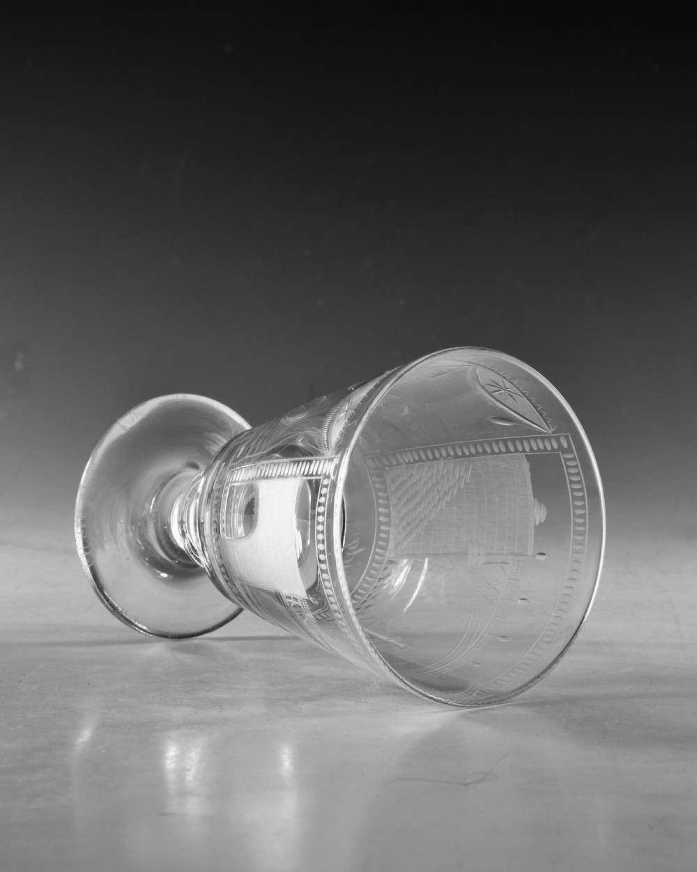 An antique clear lead glass rummer featuring detailed wheel engraving of a sailing ship beneath a bridge, set on a knopped stem and circular foot. View VII