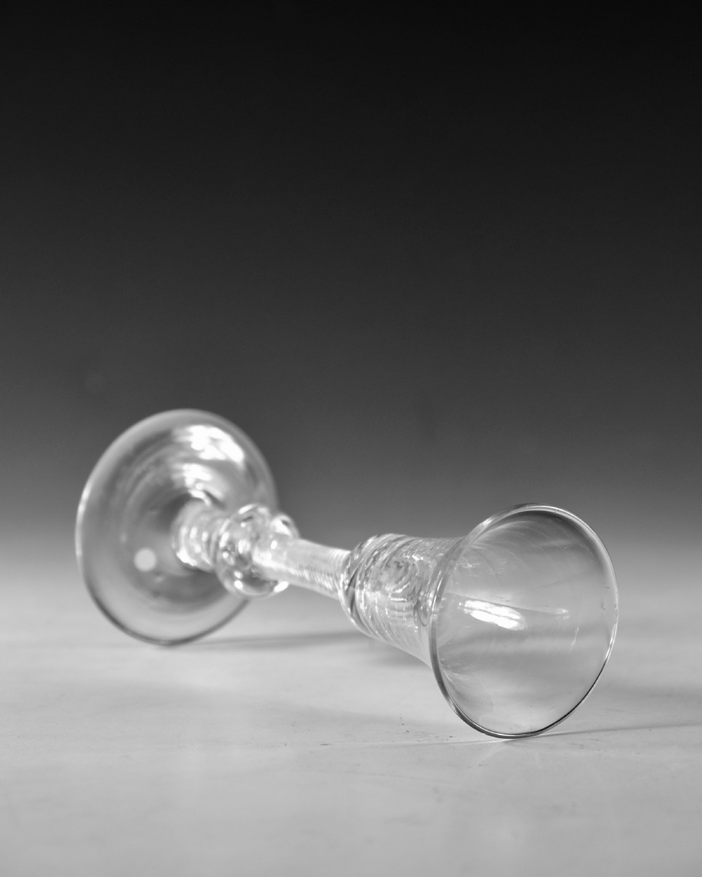 An 18th-century clear glass wine goblet featuring a flared bell bowl resting on a composite stem with internal twist decoration and a conical flat foot. View IV