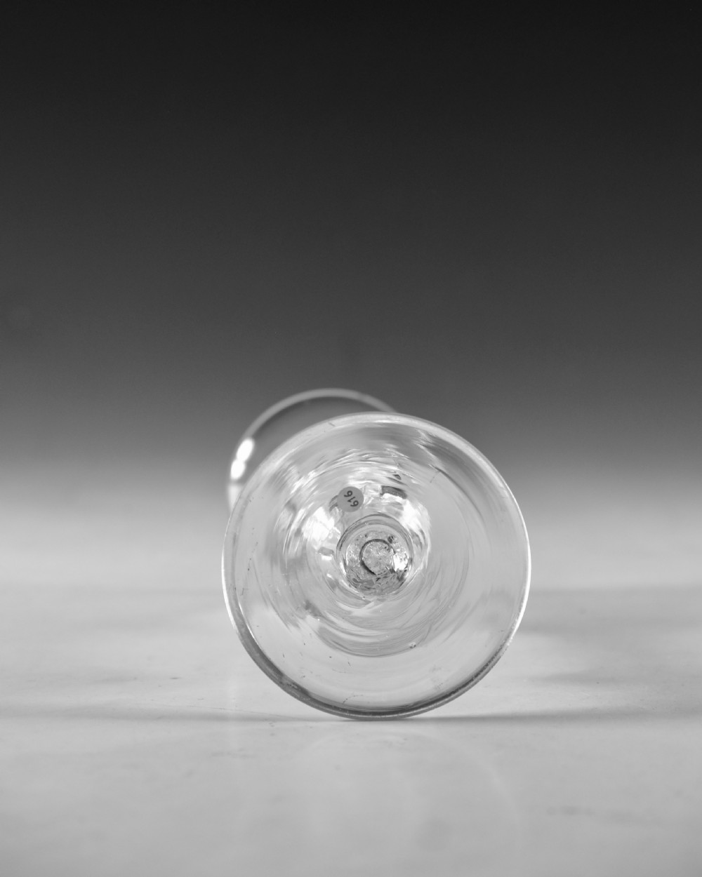 An 18th-century clear glass wine goblet featuring a flared bell bowl resting on a composite stem with internal twist decoration and a conical flat foot. View V
