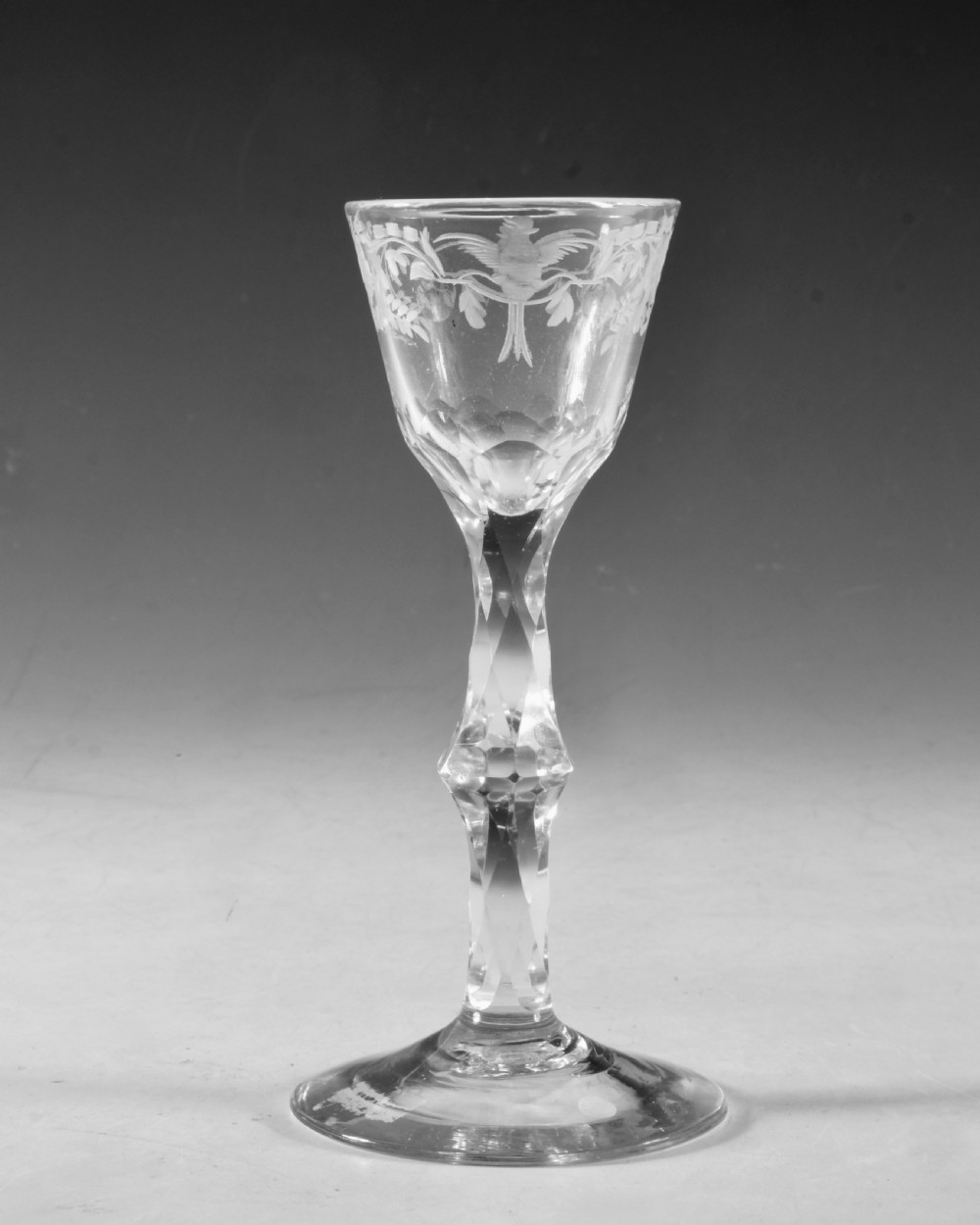 An 18th-century clear glass wine goblet featuring a wheel-engraved bird motif on the rounded bowl and a diamond-facet cut stem resting on a flat circular base. View II