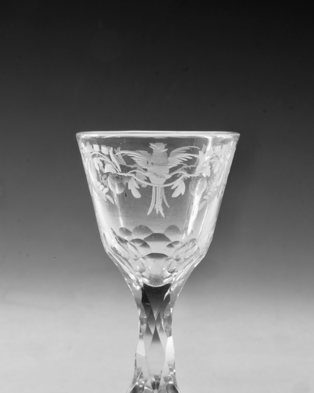 An 18th-century clear glass wine goblet featuring a wheel-engraved bird motif on the rounded bowl and a diamond-facet cut stem resting on a flat circular base. View III