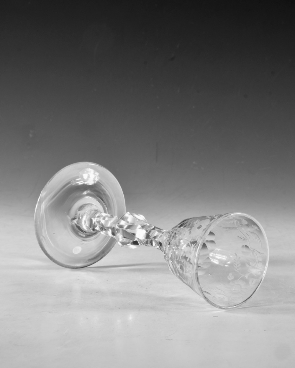 An 18th-century clear glass wine goblet featuring a wheel-engraved bird motif on the rounded bowl and a diamond-facet cut stem resting on a flat circular base. View VI