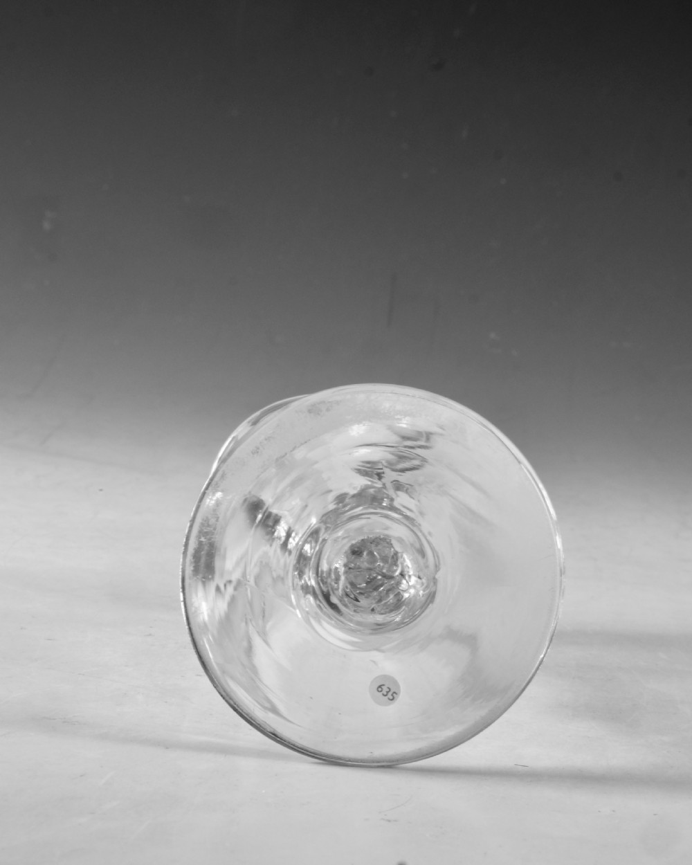 An 18th-century clear glass wine goblet featuring a wheel-engraved bird motif on the rounded bowl and a diamond-facet cut stem resting on a flat circular base. View VII