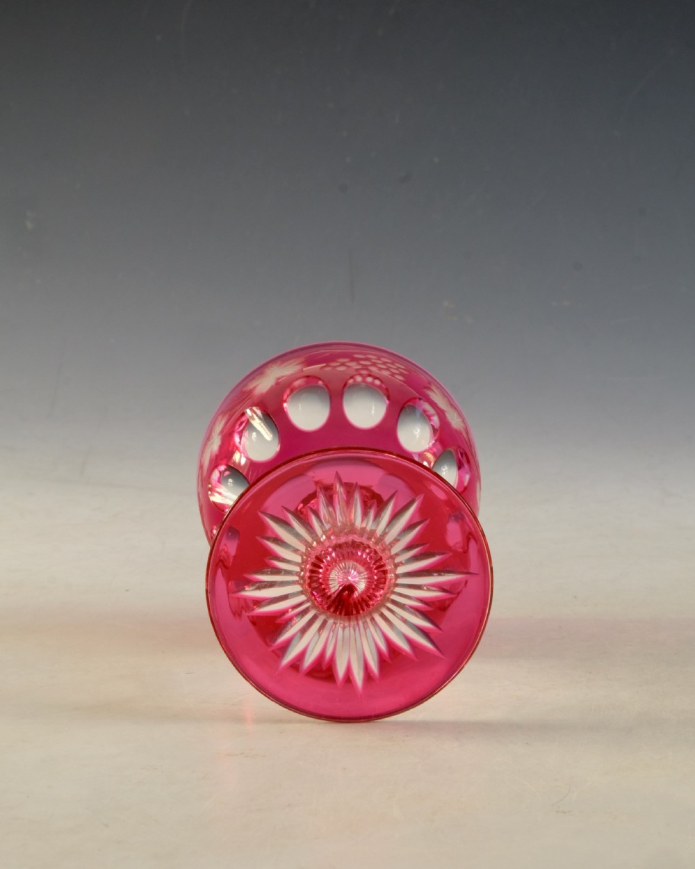 An antique Victorian wine glass featuring a ruby red overlay cut to clear with wheel-engraved grapevine motifs, a faceted stem, and a star-cut foot. View V