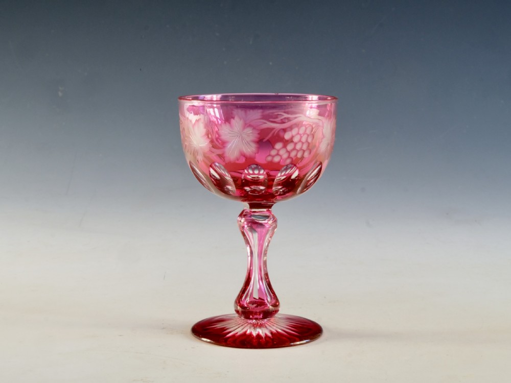 An antique Victorian wine glass featuring a ruby red overlay cut to clear with wheel-engraved grapevine motifs, a faceted stem, and a star-cut foot. View VI