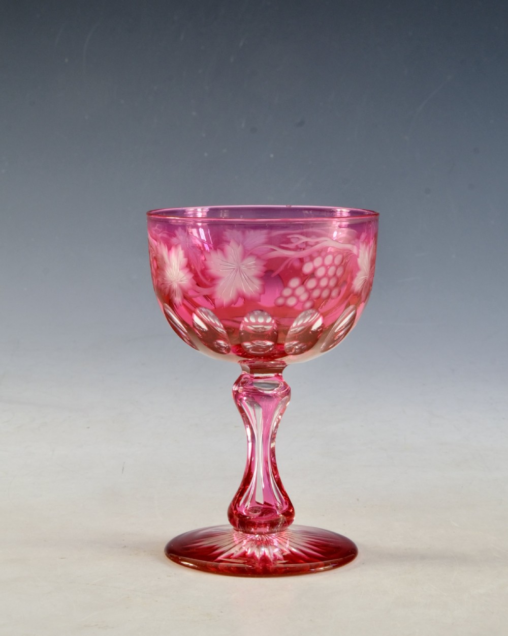 An antique Victorian wine glass featuring a ruby red overlay cut to clear with wheel-engraved grapevine motifs, a faceted stem, and a star-cut foot. View VII