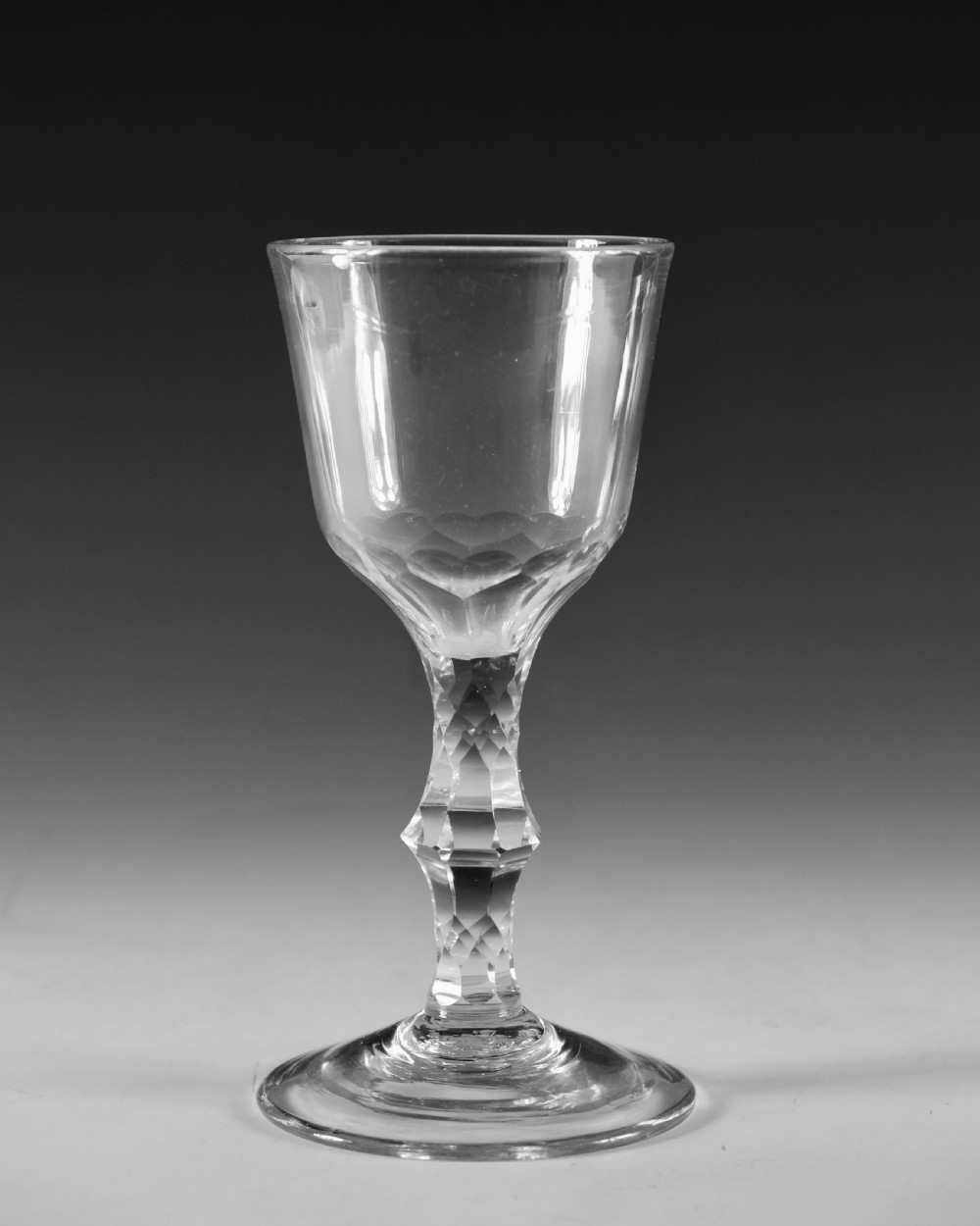 An 18th-century clear lead glass goblet featuring a faceted diamond-cut stem and a round bowl resting on a flat conical foot. View II