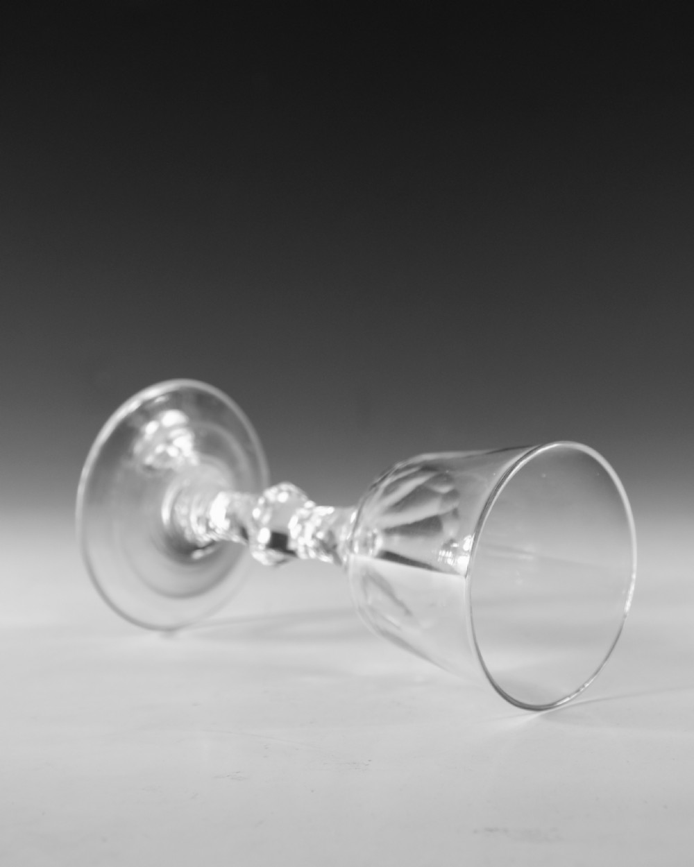 An 18th-century clear lead glass goblet featuring a faceted diamond-cut stem and a round bowl resting on a flat conical foot. View IV