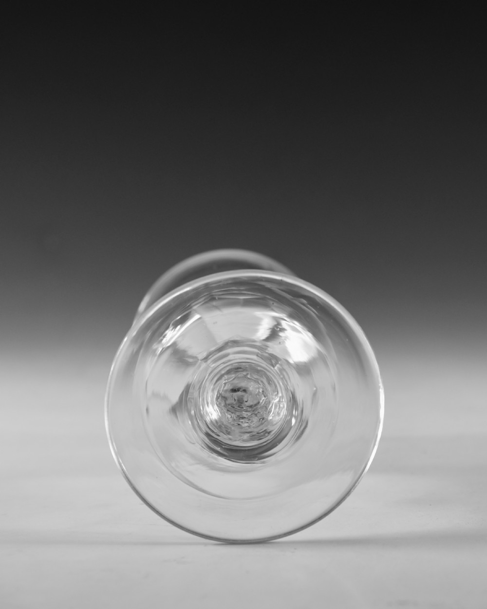 An 18th-century clear lead glass goblet featuring a faceted diamond-cut stem and a round bowl resting on a flat conical foot. View V