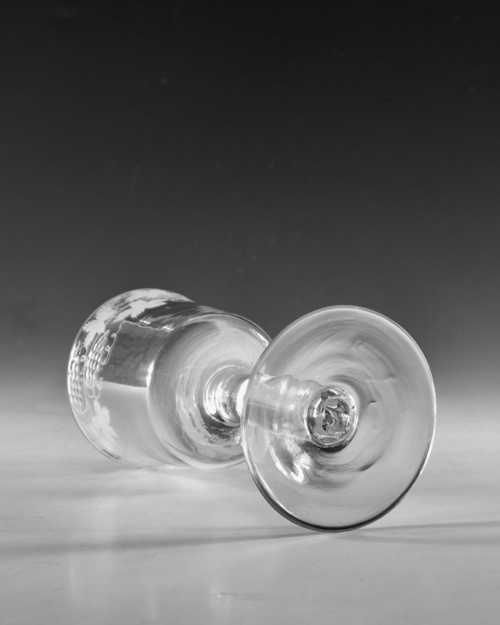 A pair of 18th-century clear lead glass goblets featuring plain straight stems and wheel-engraved grapevine motifs around the rims. View VIII