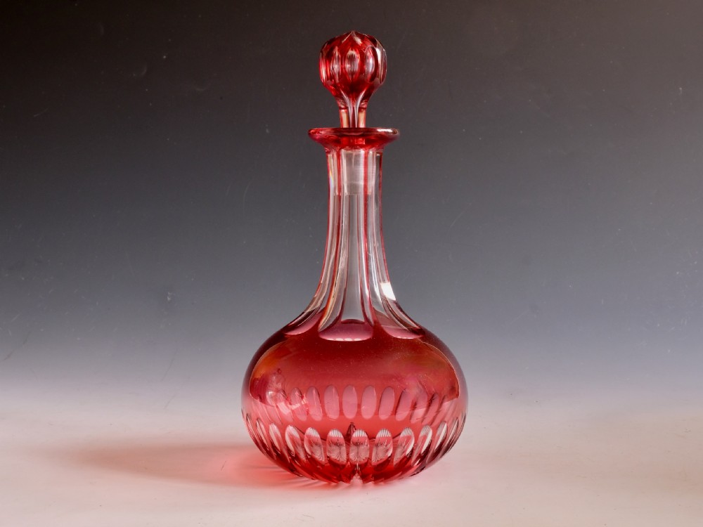 A mid-Victorian ruby overlay cut glass decanter with a matching faceted stopper and slice-cut neck.