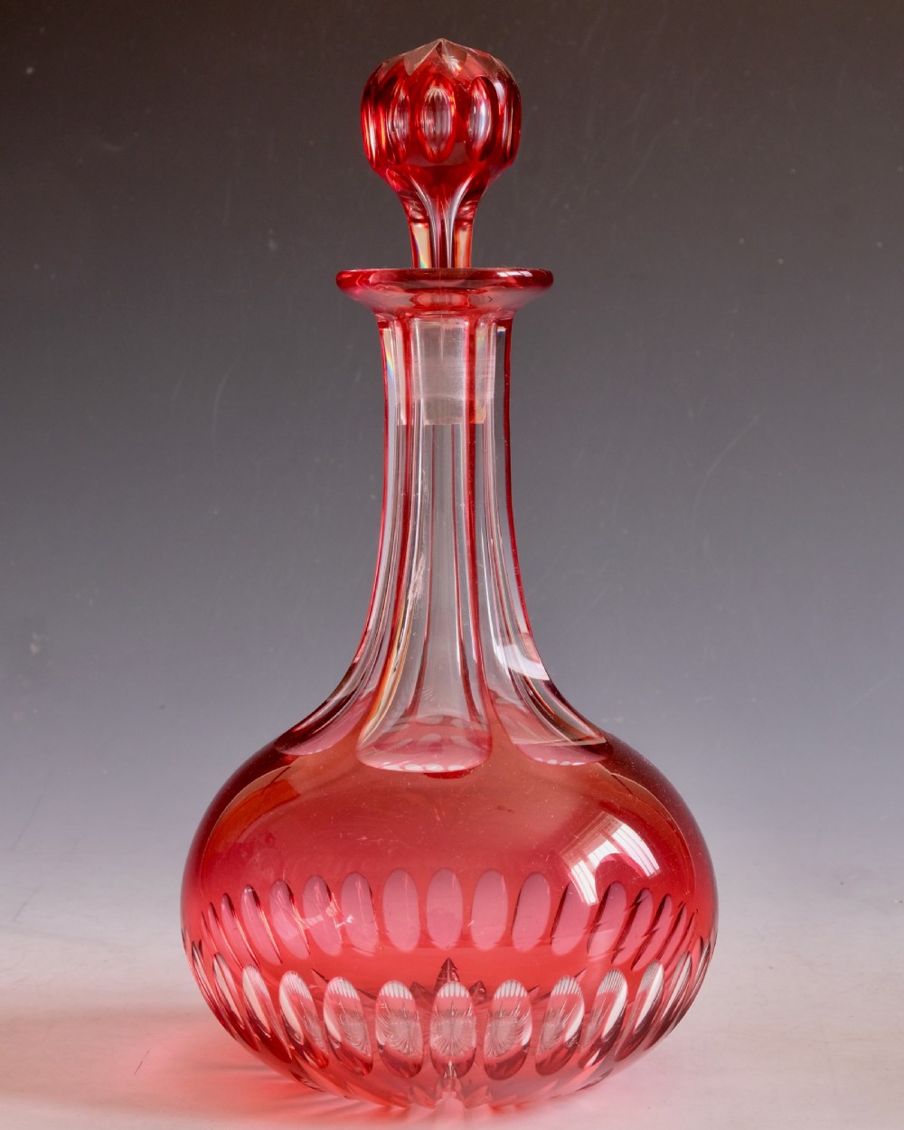 A mid-Victorian ruby overlay cut glass decanter with a matching faceted stopper and slice-cut neck. View II